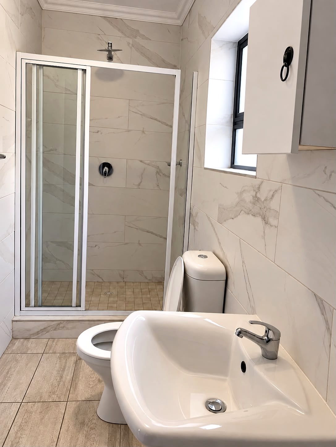 A 12B en-suite bathroom with a glass shower and marble-look tiles
