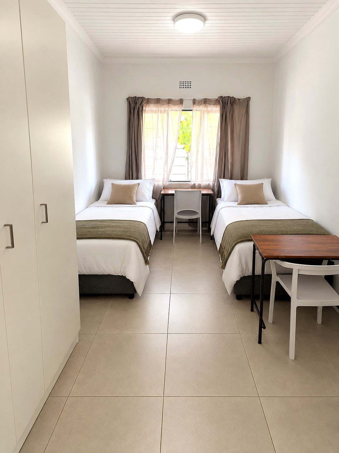 A Caledon sharing room with two made beds either side of the window