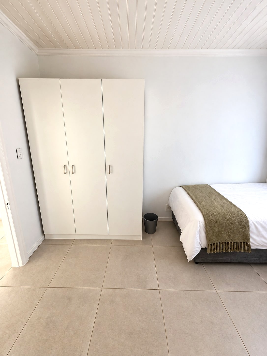 A Caledon room with a tall built-in wardrobe beside a made bed