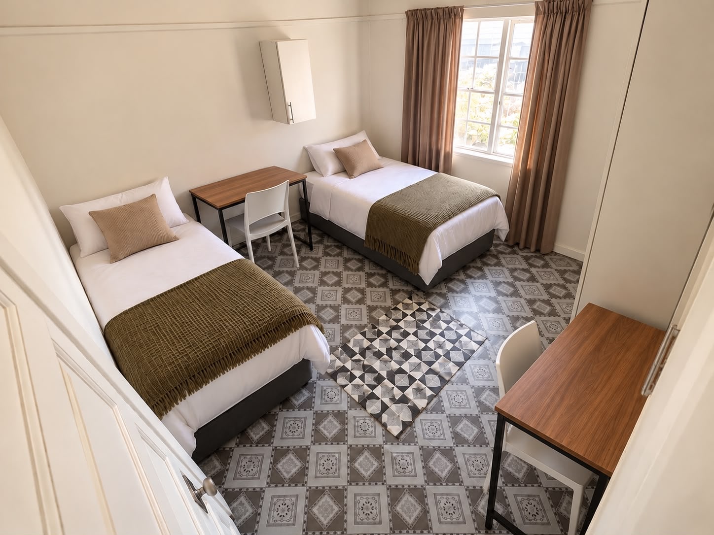 An Inspan sharing room with two beds, two desks and a window